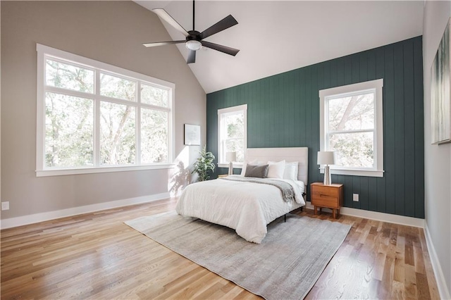 bedroom with ceiling fan, baseboards, high vaulted ceiling, and wood finished floors