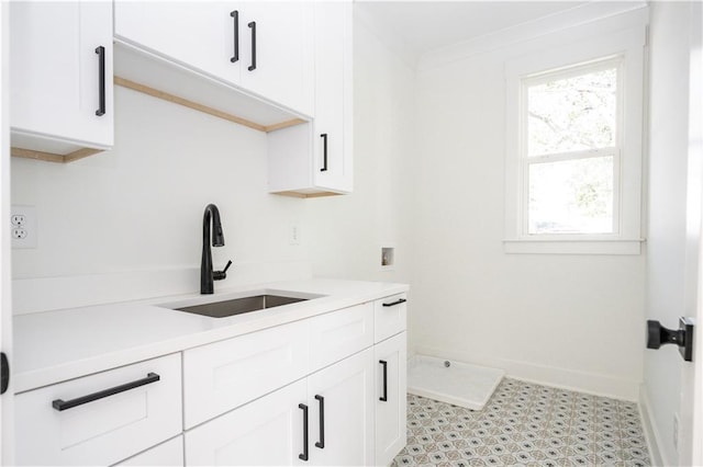 kitchen with white cabinetry, light countertops, and a sink