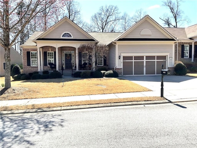 view of front of house featuring brick siding, a porch, an attached garage, driveway, and a front lawn