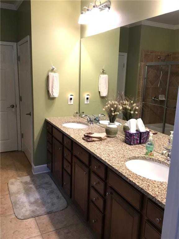 bathroom featuring double vanity, a stall shower, a sink, and crown molding