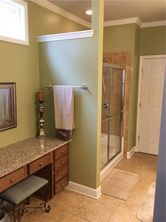 bathroom featuring ornamental molding, a shower stall, vanity, baseboards, and tile patterned floors