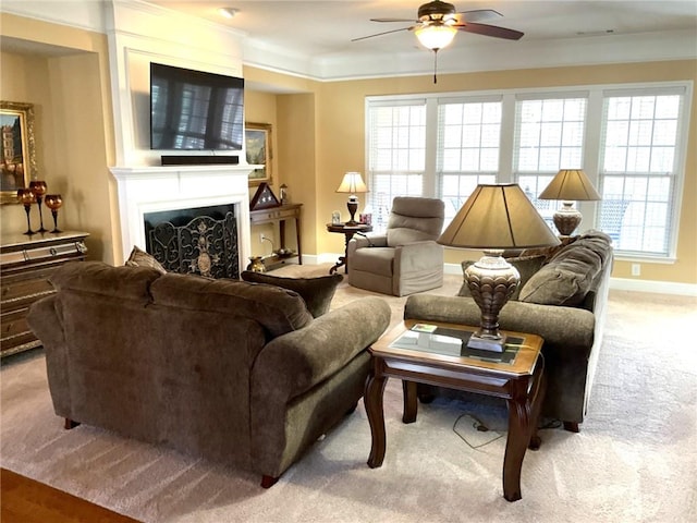 living room featuring baseboards, a ceiling fan, ornamental molding, carpet, and a fireplace