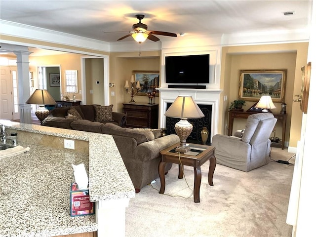 living room with crown molding, a fireplace, decorative columns, light colored carpet, and visible vents