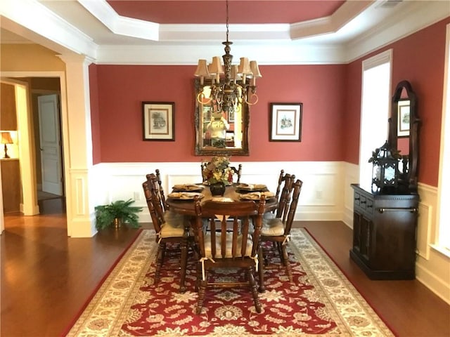 dining room featuring a raised ceiling, wainscoting, crown molding, and wood finished floors