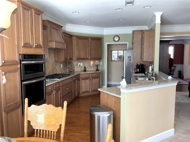 kitchen with stainless steel appliances, premium range hood, a sink, tasteful backsplash, and crown molding