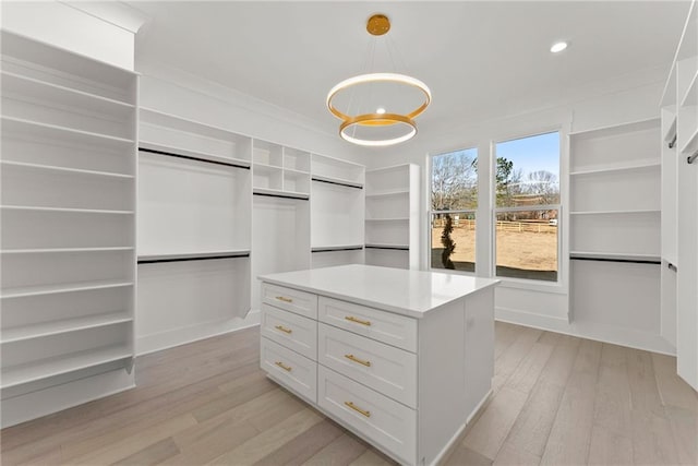 walk in closet with a notable chandelier and light hardwood / wood-style floors