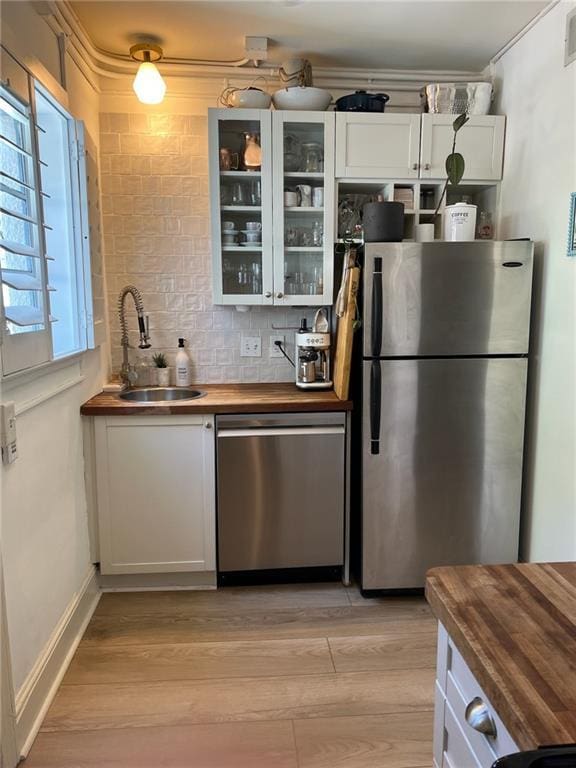 kitchen with sink, white cabinetry, appliances with stainless steel finishes, and wooden counters