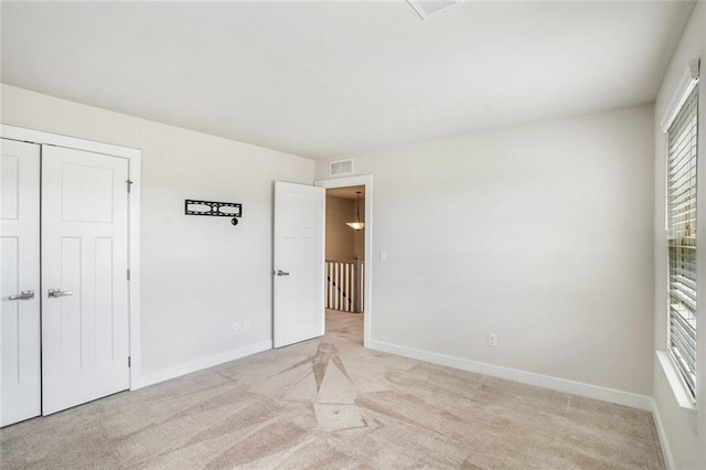 unfurnished bedroom with light carpet and a closet