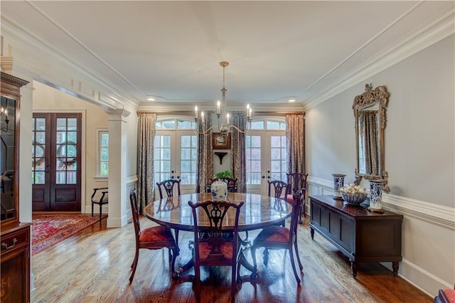 dining room with crown molding, french doors, wood-type flooring, and an inviting chandelier