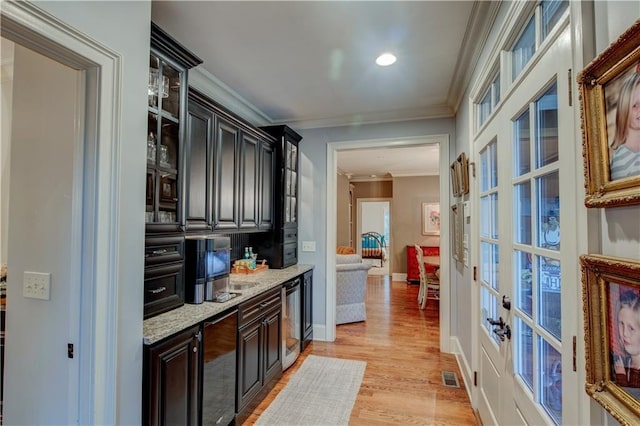 bar featuring light stone counters, light hardwood / wood-style flooring, beverage cooler, and ornamental molding