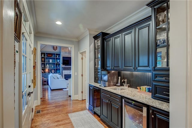 bar featuring light stone countertops, light wood-type flooring, sink, wine cooler, and a stone fireplace