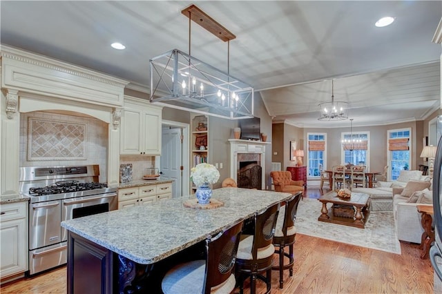 kitchen featuring a kitchen breakfast bar, tasteful backsplash, stainless steel gas range oven, a center island, and hanging light fixtures