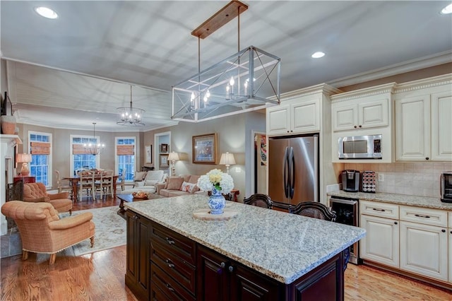 kitchen with tasteful backsplash, ornamental molding, stainless steel appliances, beverage cooler, and decorative light fixtures