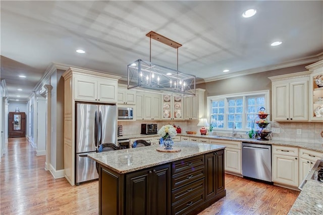 kitchen with a center island, hanging light fixtures, decorative backsplash, light stone countertops, and appliances with stainless steel finishes