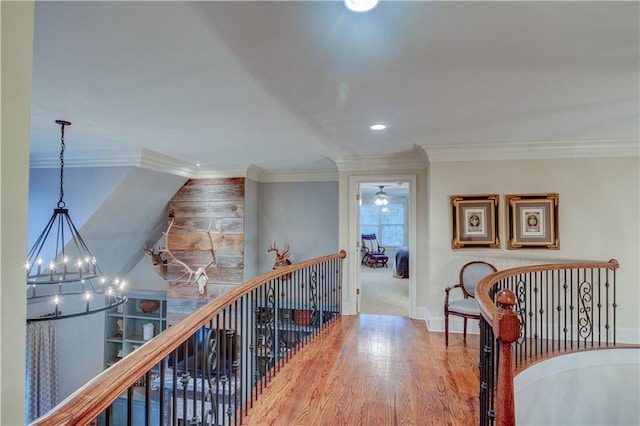 hallway with hardwood / wood-style floors, crown molding, and a chandelier