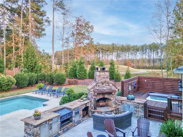 view of pool with an outdoor stone fireplace, a patio area, and an outdoor kitchen