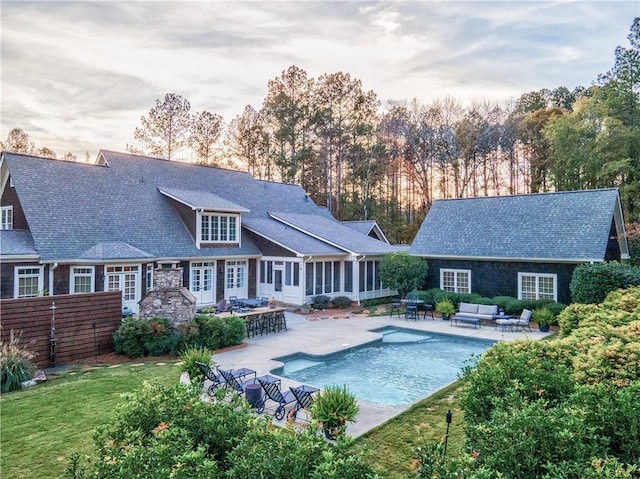 rear view of property featuring a sunroom, a patio area, an outdoor hangout area, and french doors