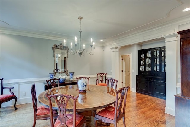 dining space with a notable chandelier, light hardwood / wood-style flooring, crown molding, and decorative columns