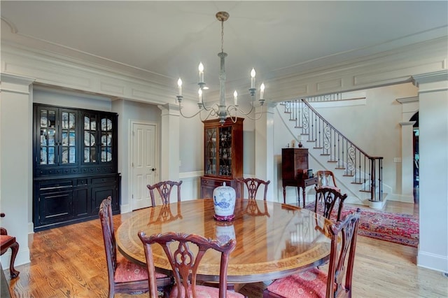 dining area featuring light hardwood / wood-style floors, ornamental molding, and an inviting chandelier