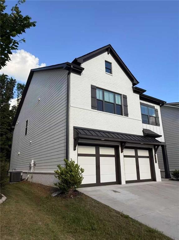 1923 Westfall Lndg, Auburn, GA 30011 - view of home's exterior featuring driveway, a garage, a standing seam roof, and a metal roof