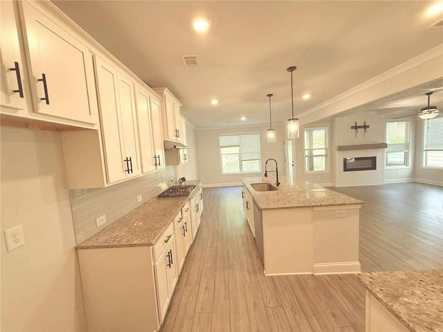 1923 Westfall Lndg, Auburn, GA 30011 - kitchen featuring light wood-style flooring, stainless steel gas cooktop, crown molding, white cabinets, and light stone countertops