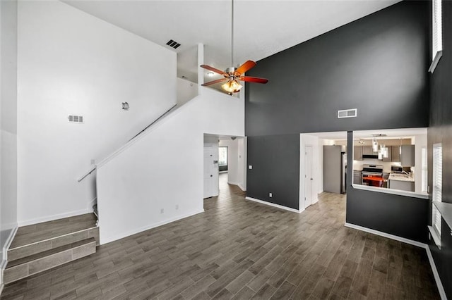 unfurnished living room featuring dark wood-type flooring, high vaulted ceiling, and ceiling fan