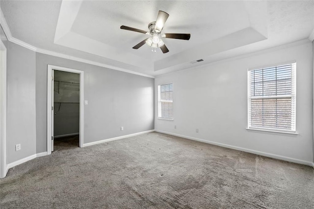 unfurnished bedroom with a raised ceiling, ornamental molding, and carpet