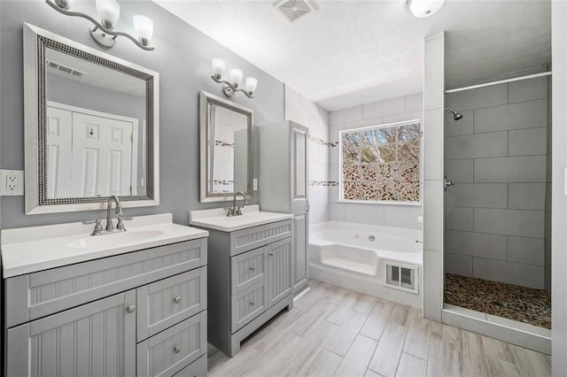 bathroom with vanity, hardwood / wood-style flooring, independent shower and bath, and a textured ceiling