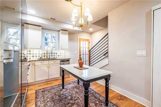 kitchen featuring white cabinets, backsplash, a chandelier, and sink