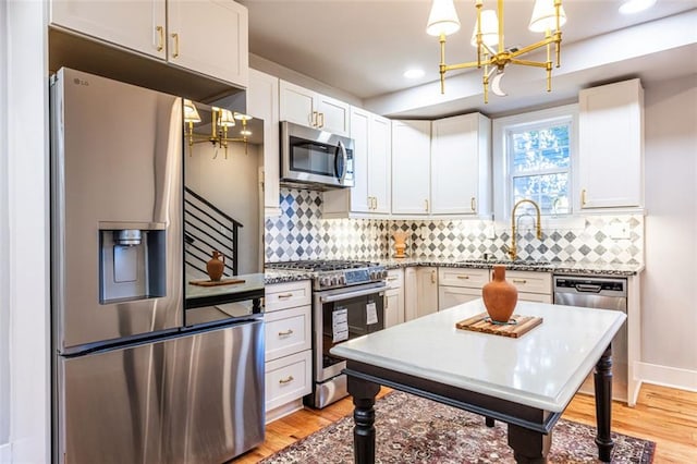 kitchen with appliances with stainless steel finishes, white cabinetry, hanging light fixtures, and sink