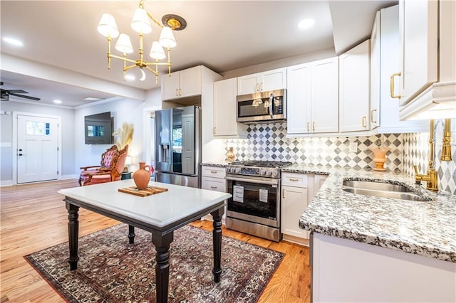 kitchen featuring decorative light fixtures, stainless steel appliances, white cabinetry, and sink