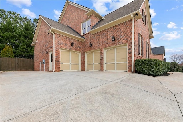 view of home's exterior with brick siding, driveway, and fence