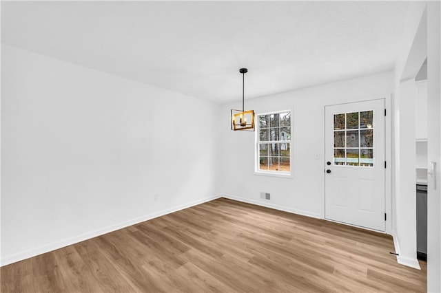 unfurnished dining area with visible vents, light wood-style flooring, baseboards, and an inviting chandelier