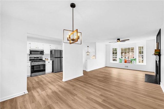 kitchen with white cabinets, open floor plan, light countertops, appliances with stainless steel finishes, and pendant lighting