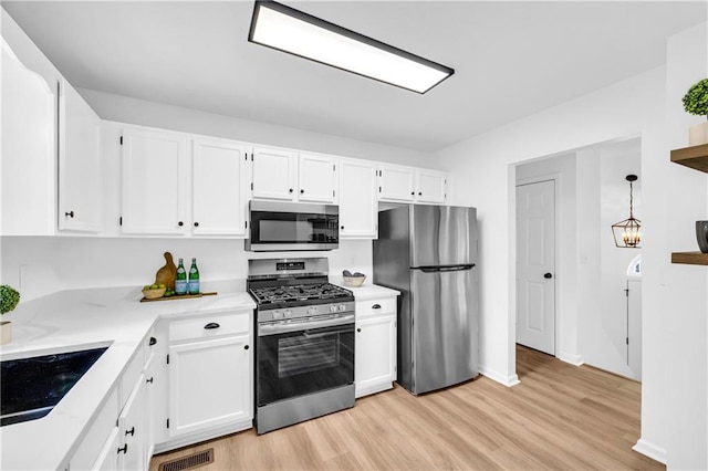 kitchen featuring pendant lighting, stainless steel appliances, light countertops, white cabinets, and a sink