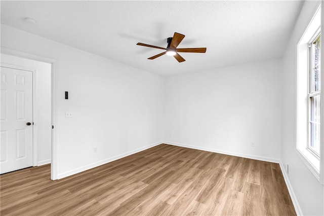 empty room with light wood finished floors, baseboards, and a ceiling fan