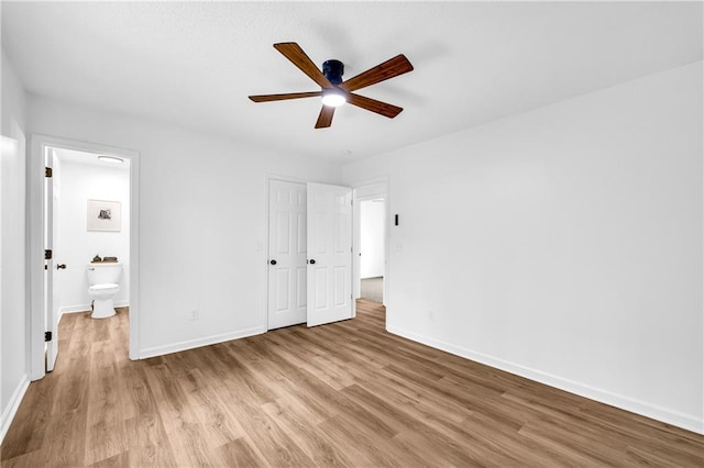 unfurnished bedroom with baseboards, ensuite bathroom, and light wood-style floors