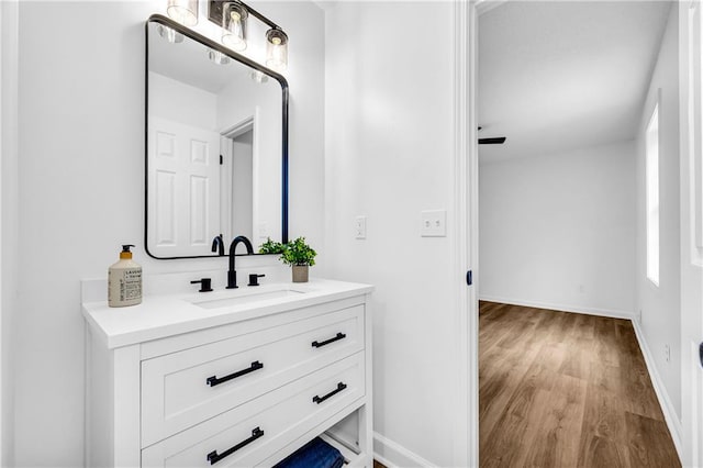 bathroom with wood finished floors, vanity, and baseboards