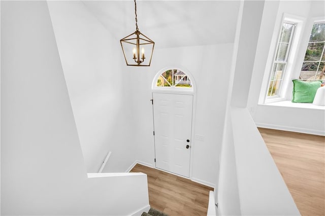 entrance foyer with a chandelier, wood finished floors, stairs, and baseboards