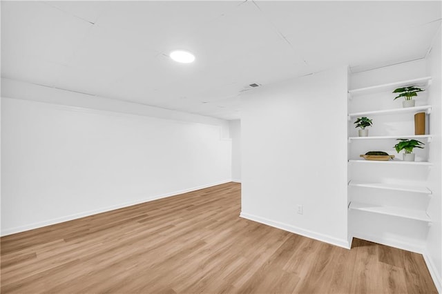 spare room featuring visible vents, light wood-style flooring, and baseboards