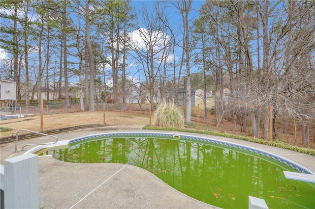 outdoor pool with fence, a patio, and a diving board