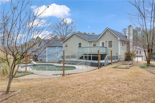 back of house with a yard, a chimney, an outdoor pool, and a wooden deck