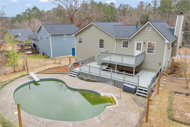 rear view of house featuring a fenced in pool, a chimney, roof with shingles, fence, and a wooden deck