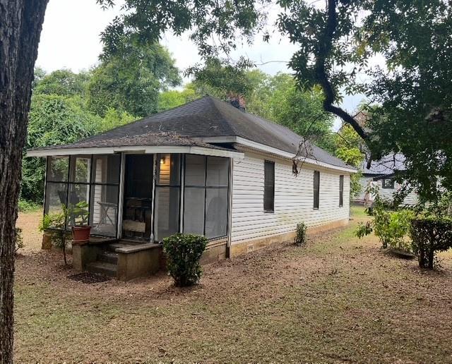 rear view of property featuring a sunroom and roof with shingles