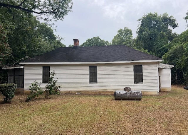 back of house featuring a lawn and a chimney