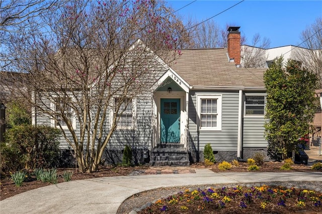 view of front of property featuring entry steps, a shingled roof, and a chimney