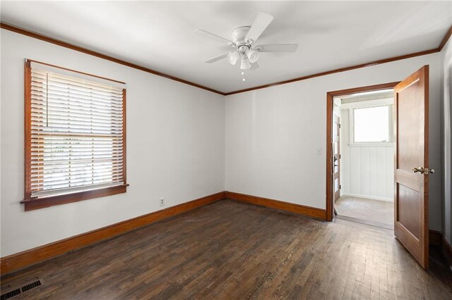 empty room with ornamental molding, visible vents, baseboards, and wood finished floors