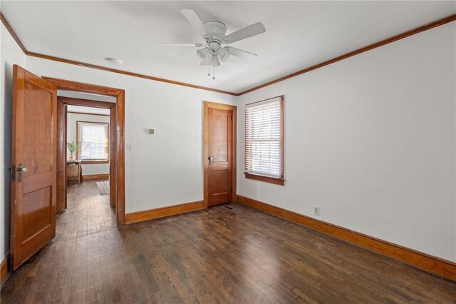 spare room with a healthy amount of sunlight, dark wood-style floors, baseboards, and crown molding