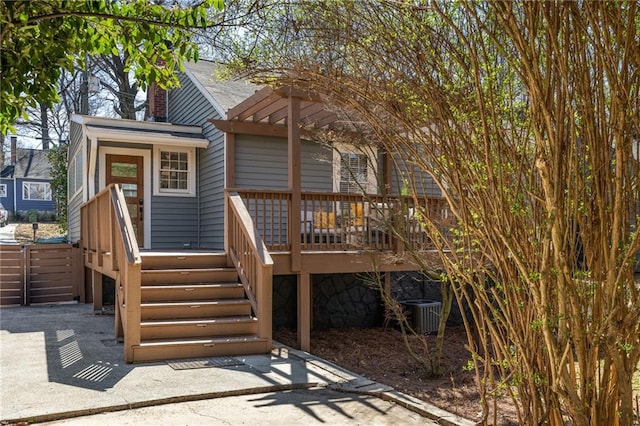 exterior space with stairs, central AC unit, a deck, and roof with shingles