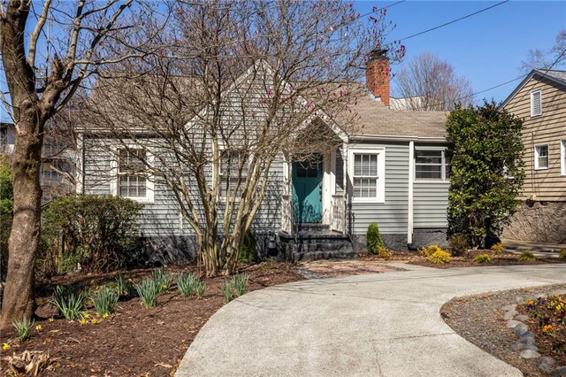 view of front of house featuring concrete driveway and a chimney